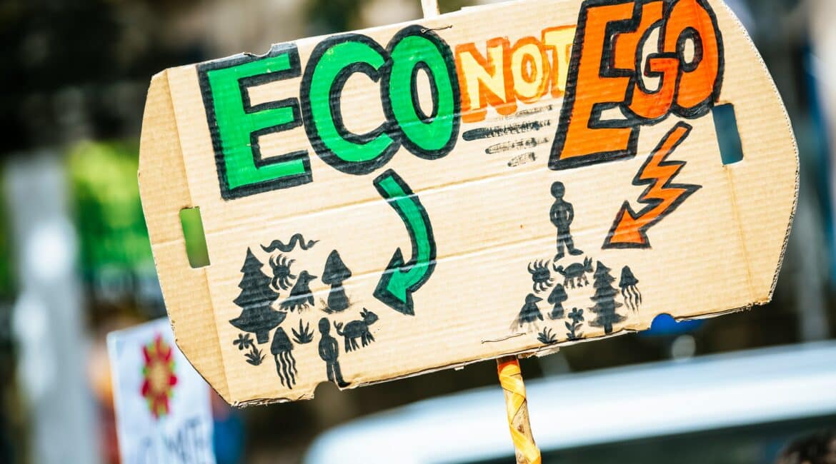 Eco not Ego The image shows a cardboard protest sign with the phrase "ECO NOT EGO" prominently displayed, highlighting a message of environmental responsibility over self-centred actions. The sign features colourful, hand-drawn illustrations of a healthy ecosystem on the left, including trees, birds, and animals, and a contrasting scene on the right depicting environmental degradation. This image underscores the importance of prioritising ecological well-being in planning reforms, advocating for sustainable development practices that protect nature and combat climate change.